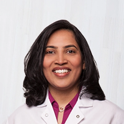 Dentist Susmitha Jasti Smiling In Lab Coat